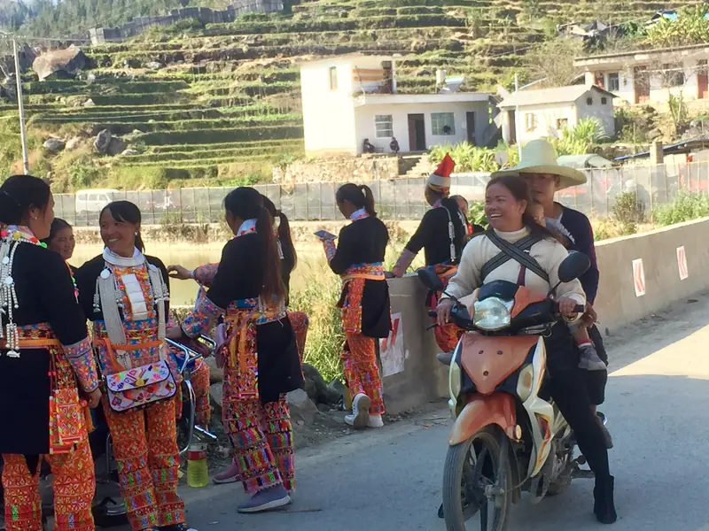 Women in traditional dress chat streetside at a village in Yunnan.