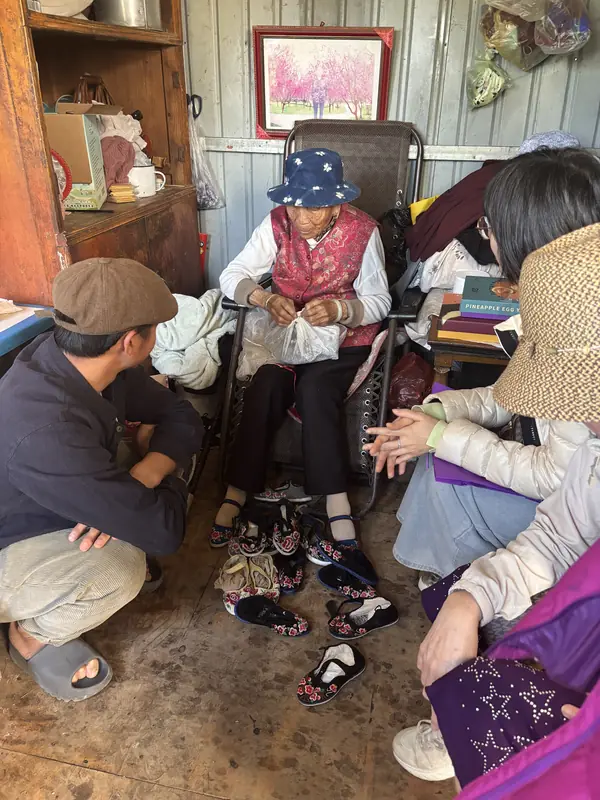 Visitors sit with an elderly woman in Tonghai village during a home visit about her foot-binding history.