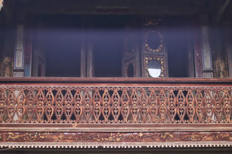 Carved wooden balcony railing inside a historic Tonghai courtyard house.