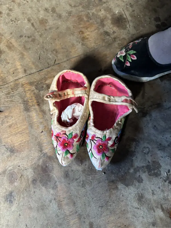 Small embroidered shoes traditionally worn by women with bound feet in Tonghai village.