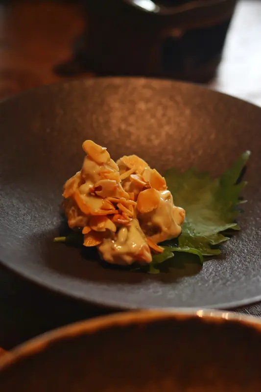 Plated vegan course with a golden garnish on a leaf, Yunnan vegan tasting menu