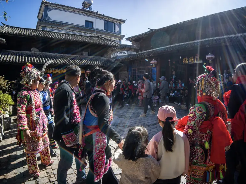 Yi minority villagers in traditional dress in a village courtyard, Yunnan