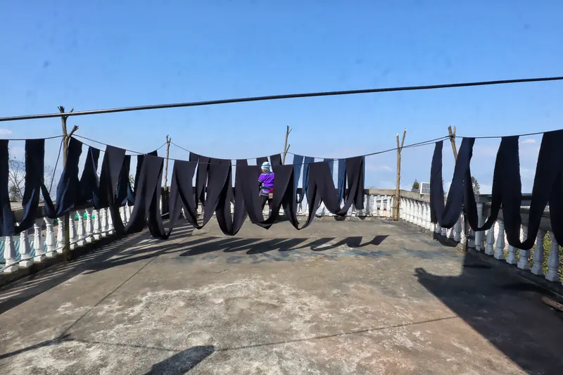 Indigo-dyed cloth hangs to dry on a Yi village rooftop.