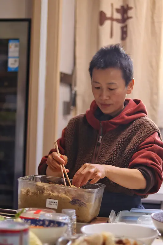Local chef stirring a pot during a vegan cooking workshop in Yunnan