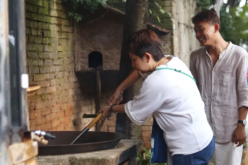 Visitors learning traditional soy sauce making over a brick furnace, Yunnan