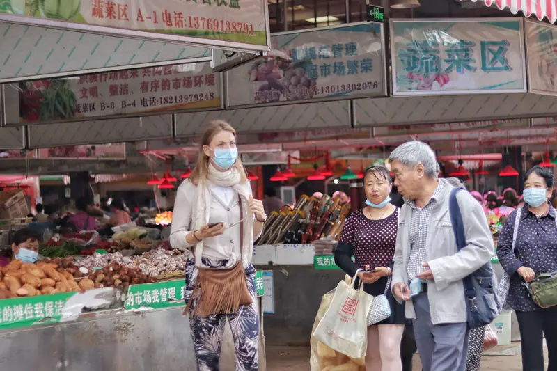 Visitors browsing fresh produce stalls at a local wet market in Yunnan