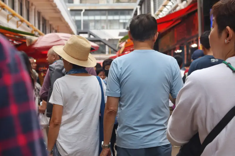 Visitors walking through a busy wet market alley on a Yunnan food tour
